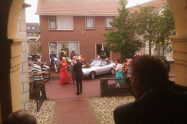 Daar komt het bruidspaar in een cabrio, begeleid door motorvriendjes van de bruidegom. foto
